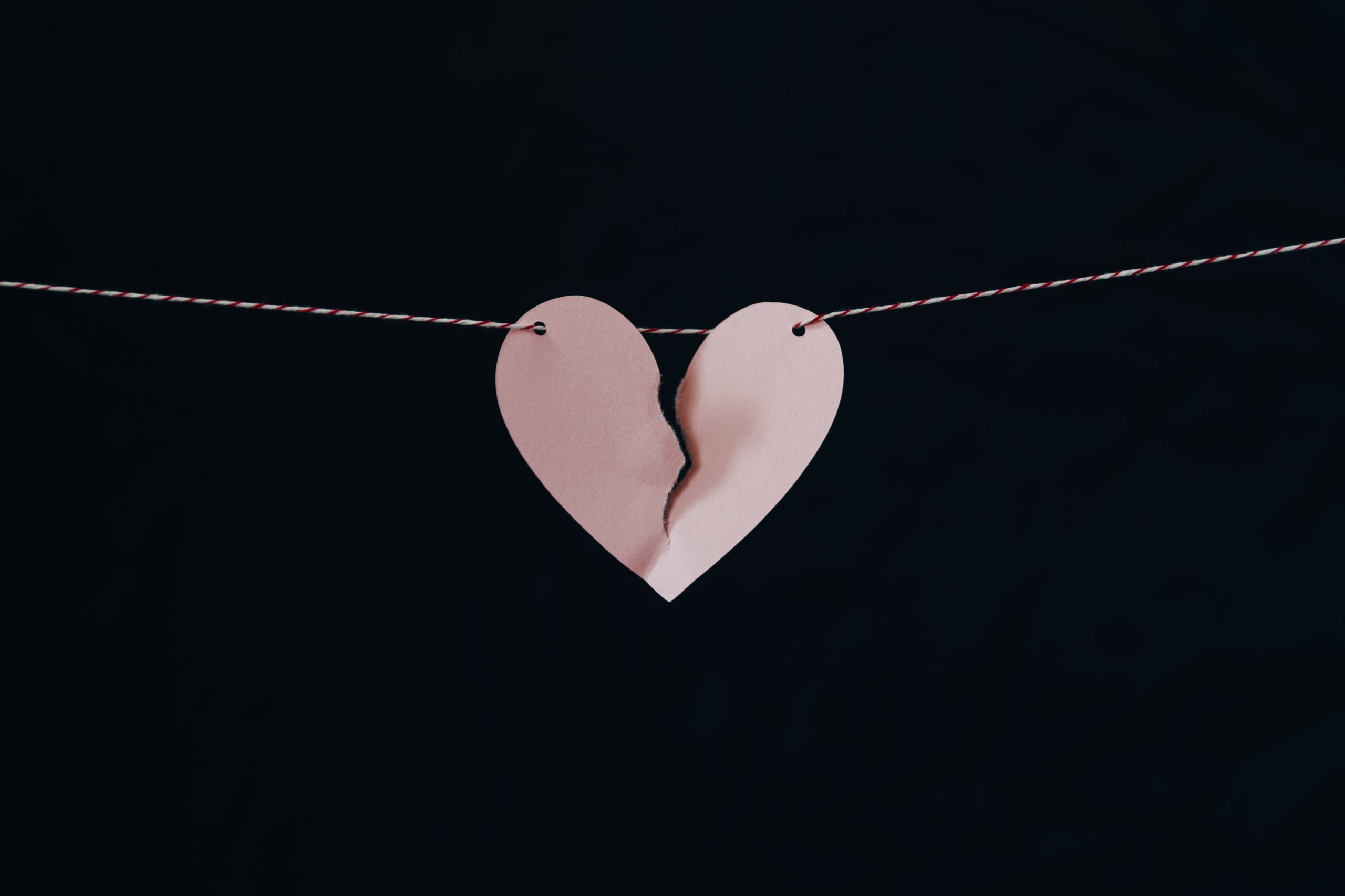 a paper pink heart on a string torn down the middle