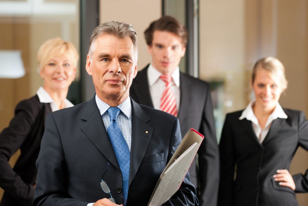 A group of veteran lawyers pose in front of a glass wall in the office