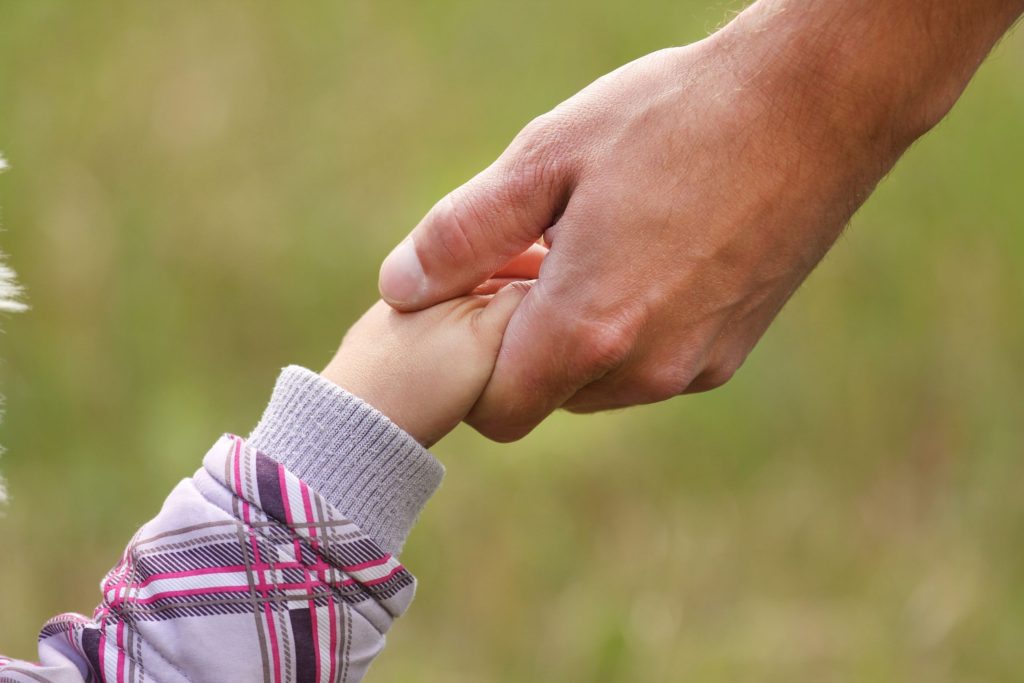 parent holds the hand of a small child