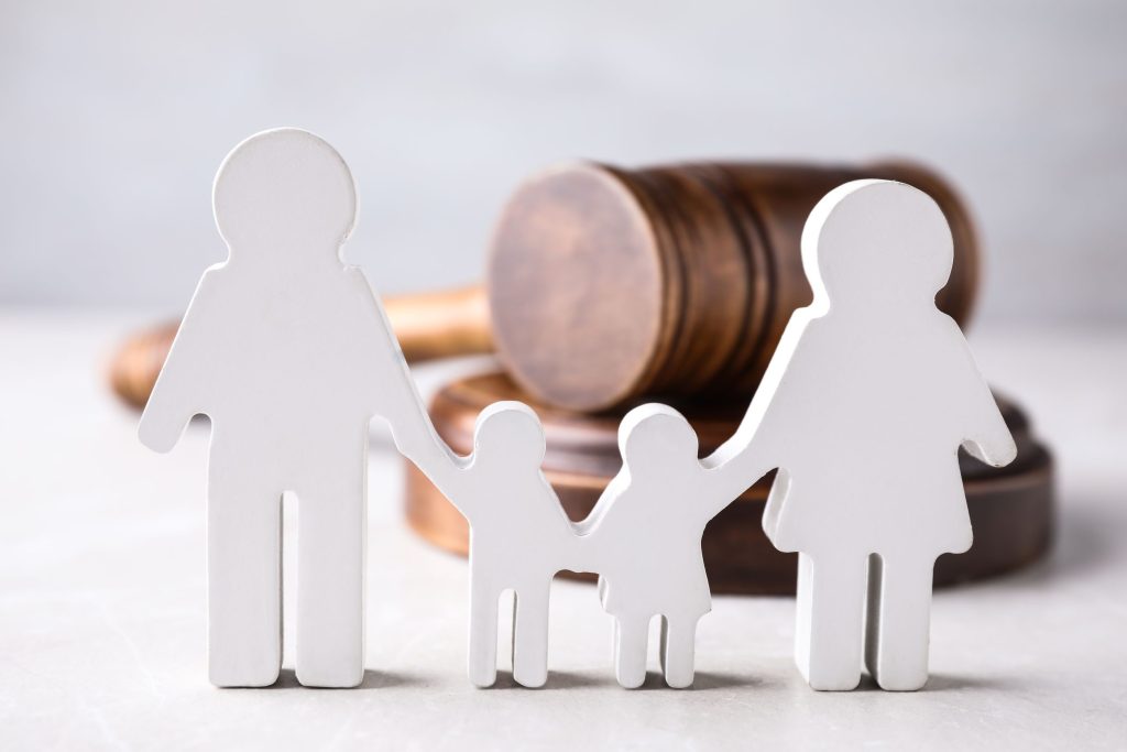 Little wooden family figures with a gavel lying behind them.