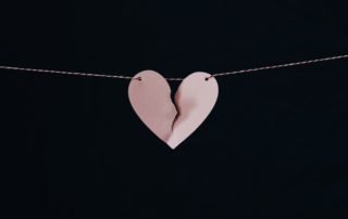 a paper pink heart on a string torn down the middle
