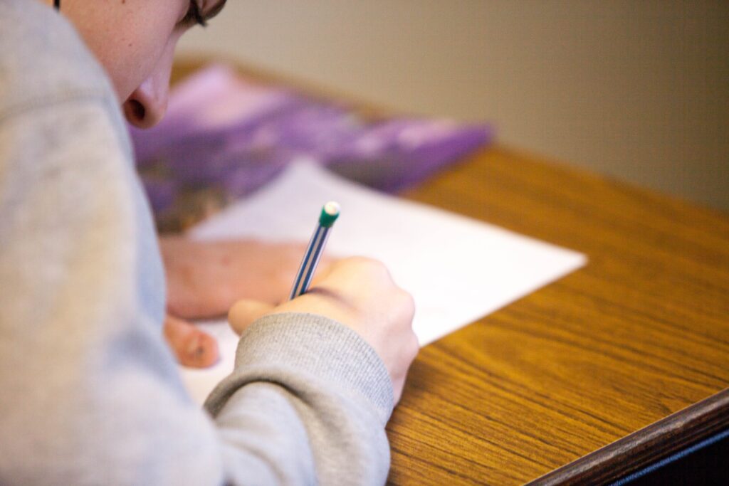 A student taking the bar exam on a wooden desk