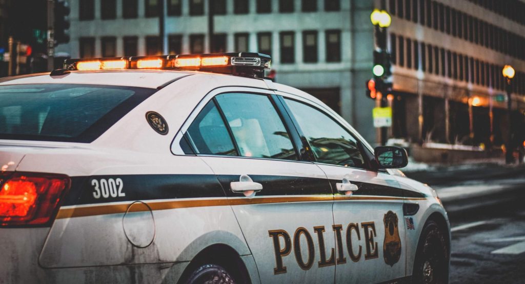 Police car pulls up to the scene of a crime in a metropolitan city