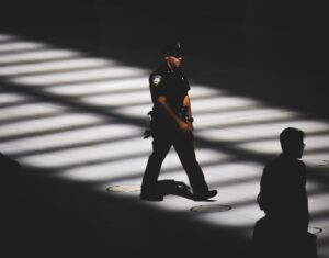 A police officer walks through a dark and mostly empty room