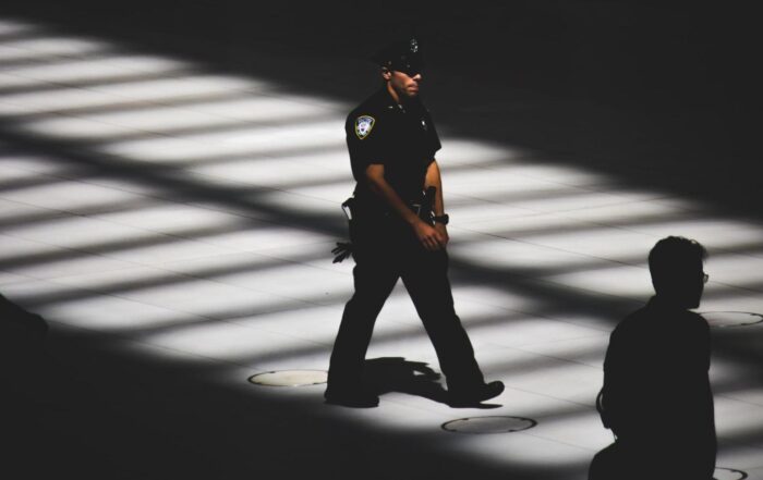 A police officer walks through a dark and mostly empty room
