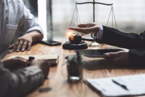 A lawyer explaining legal advice to a client at a desk with scales of justice, a gavel, and documents, illustrating when to hire a lawyer for legal assistance.